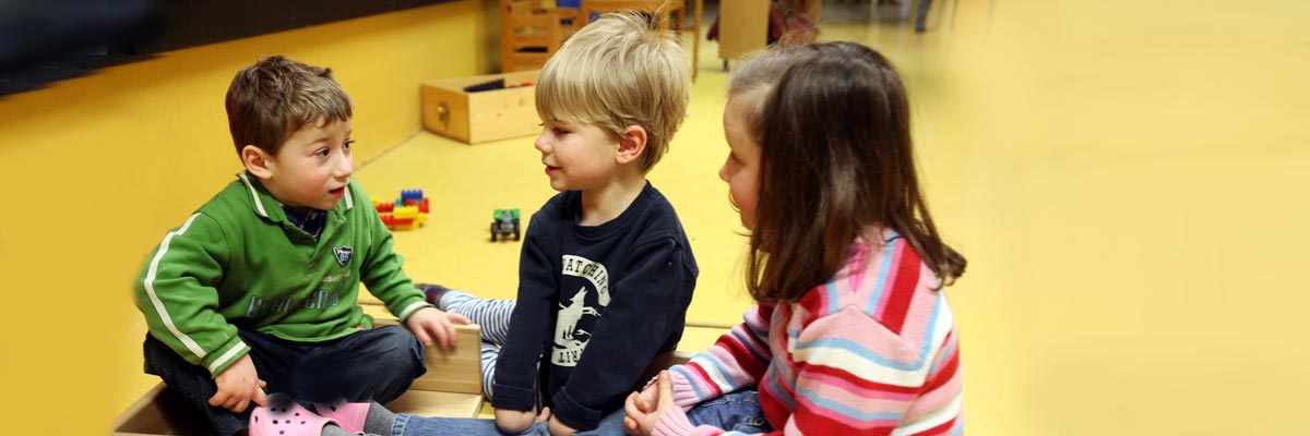Drei Kinder sitzend beim Spiel