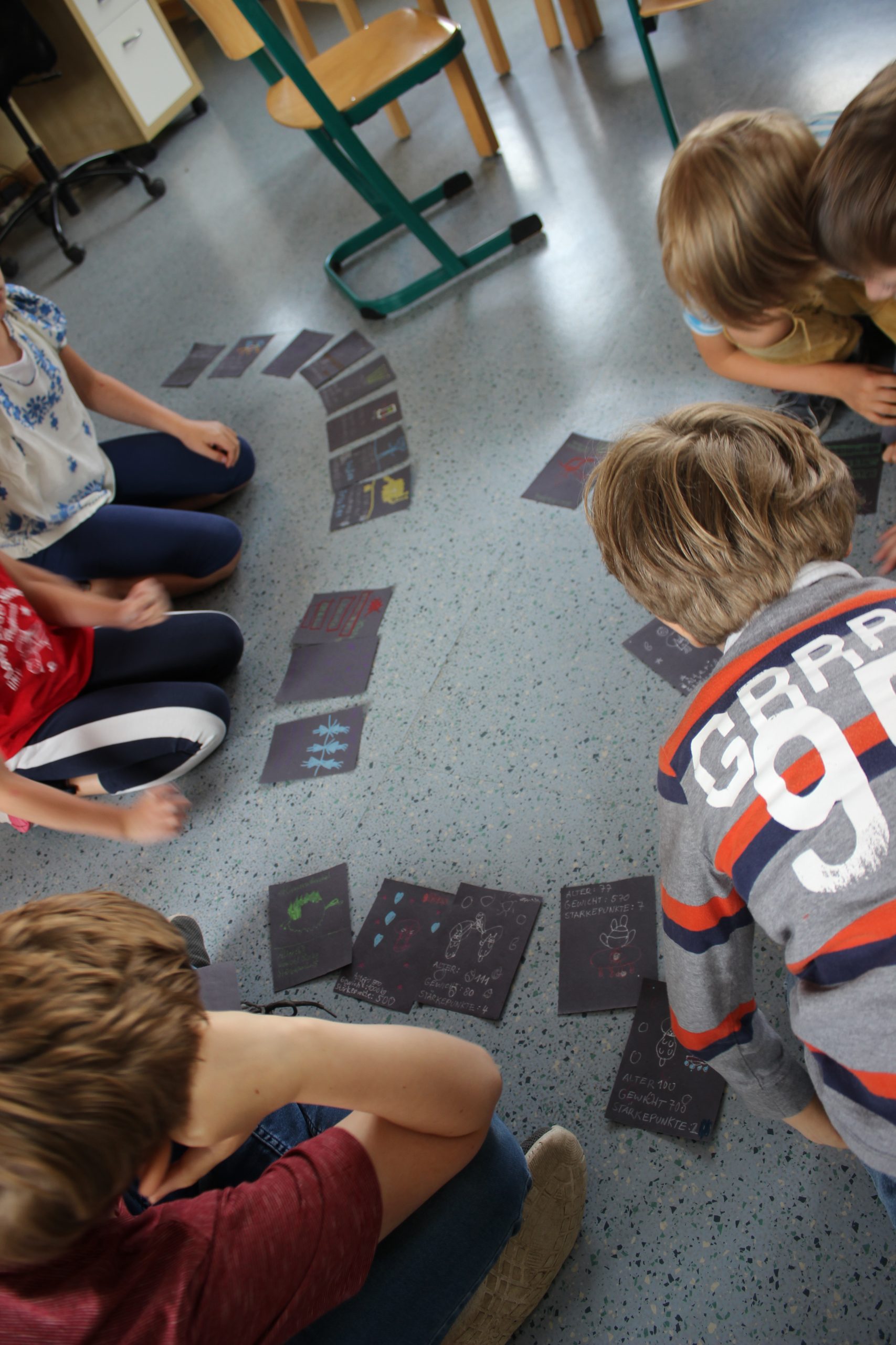 Kindern knieen vor selbstgemachten Spielkarten