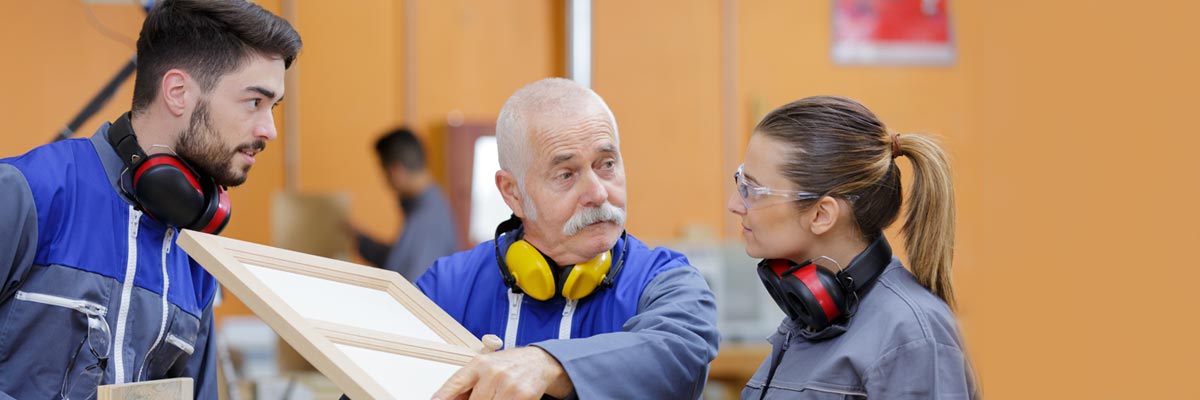 Mitarbeiter erklärt jüngeren Kollegen ein Möbelstück